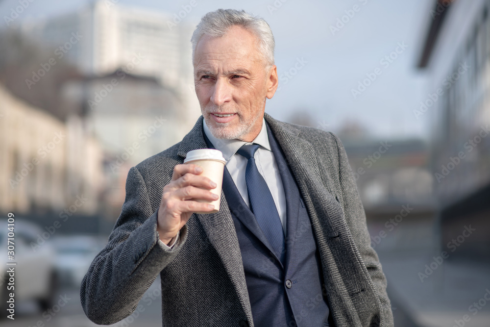 Mature man in elegant coat having coffee