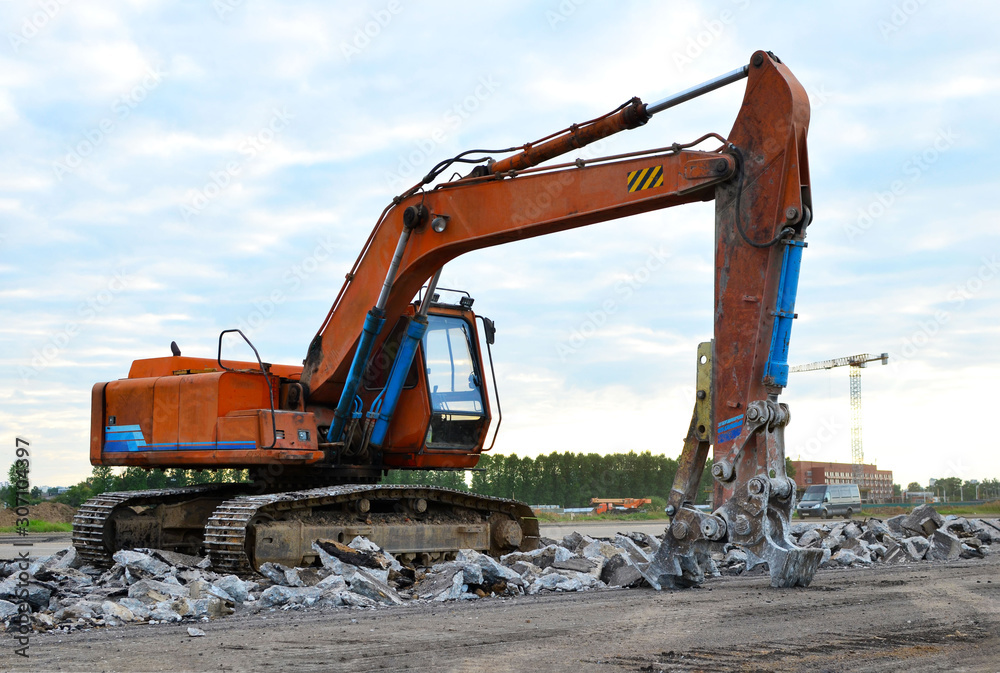 Excavator with hydraulic shears breaks asphalt on a construction site. Hydraulic shear crusher pulverizer for excavator. Heavy-duty mechanical concrete crusher. Attachments Equipment - Image Excavator with hydraulic shears breaks asphalt on a construction site. Hydraulic shear crusher pulverizer for excavator. Heavy-duty mechanical concrete crusher. Attachments Equipment - Image