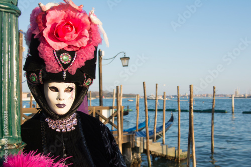 Female mask at the Venice carnival wearing a black and pink dress