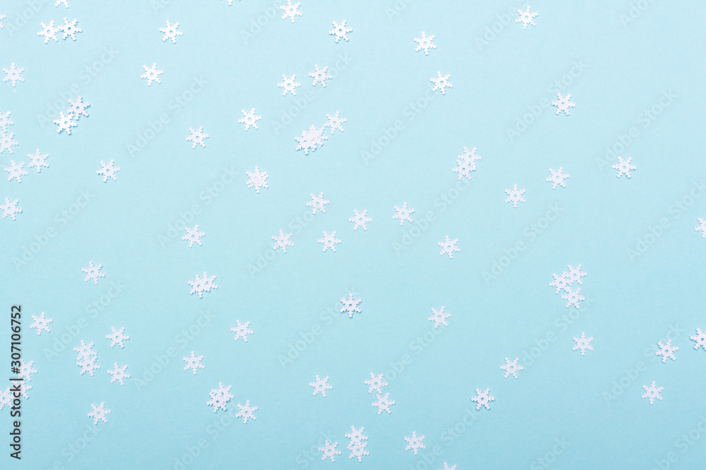 White sparkly snowflakes confetti scattered on the blue background, copy space, selective focus