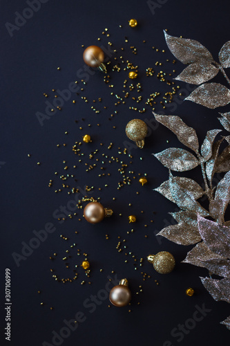 Golden Christmas decoration on dark background. Baubles and leaves. Flat lay.