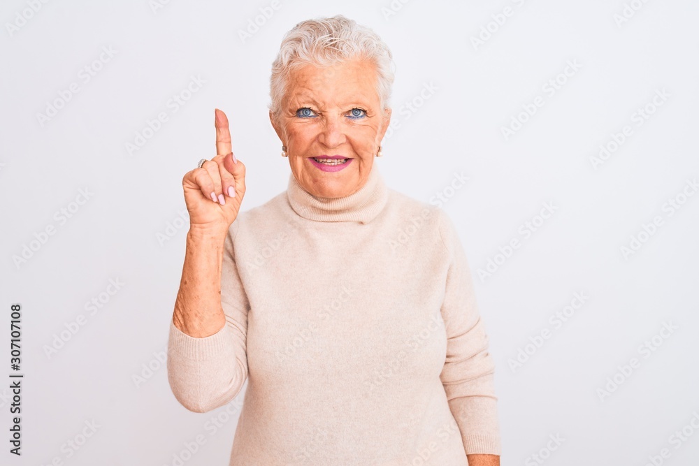 Senior grey-haired woman wearing turtleneck sweater standing over isolated white background showing and pointing up with finger number one while smiling confident and happy. Senior grey-haired woman wearing turtleneck sweater standing over isolated white background showing and pointing up with finger number one while smiling confident and happy.