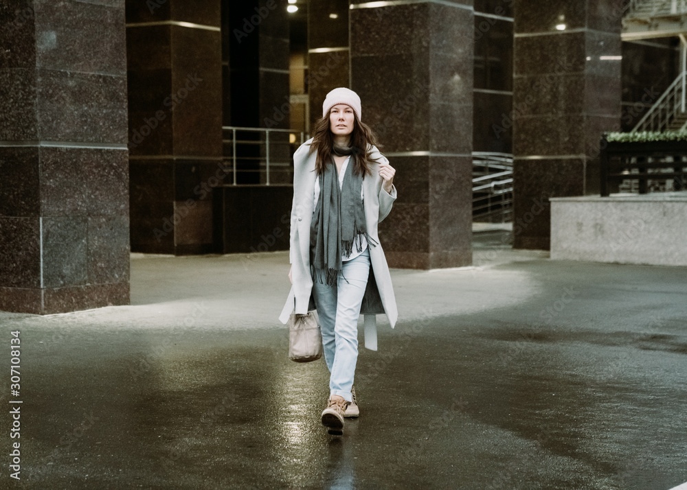 Young brunette woman walking around the city. She's wearing a gray coat and blue jeans Young brunette woman walking around the city. She's wearing a gray coat and blue jeans