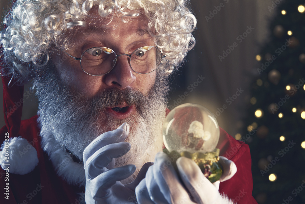 Emotional Santa Clause congratulating with New Year 2020 and Christmas. Man in traditional costume holding magic sphere ball with christmas tree on backgorund. Winter, holidays, sales. Copyspace.