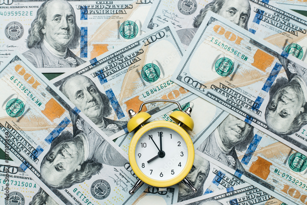Yellow alarm clock on the stack of one hundred american dollars bills. Credit, deposit and mortgage concept. Yellow alarm clock on the stack of one hundred american dollars bills. Credit, deposit and mortgage concept.