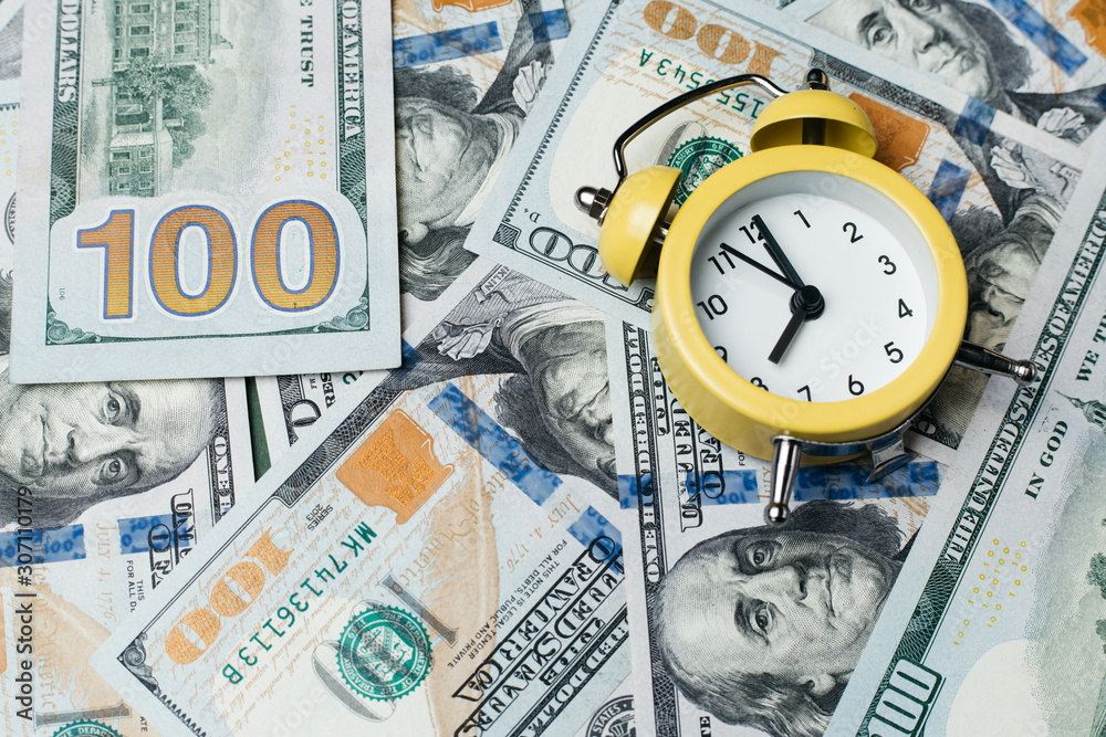 Yellow alarm clock on the stack of one hundred american dollars bills. Credit, deposit and mortgage concept. Yellow alarm clock on the stack of one hundred american dollars bills. Credit, deposit and mortgage concept.