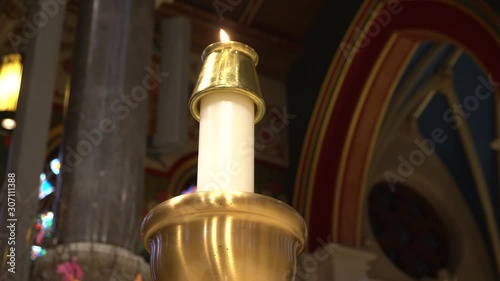 A candle that creates a beautiful background for the pleasure of your eyes. Behind, you can see the elements of the church. photo