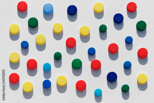 Plastic bottle caps background with colorful random pattern on white background