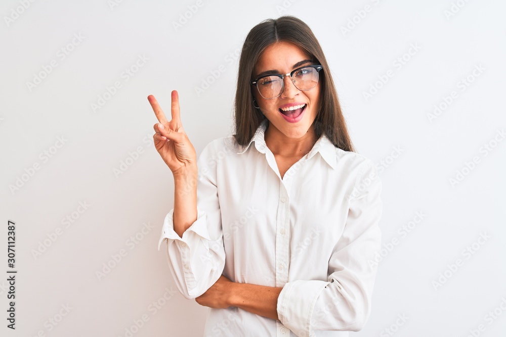 Young beautiful businesswoman wearing glasses standing over isolated white background smiling with happy face winking at the camera doing victory sign with fingers. Number two. Young beautiful businesswoman wearing glasses standing over isolated white background smiling with happy face winking at the camera doing victory sign with fingers. Number two.