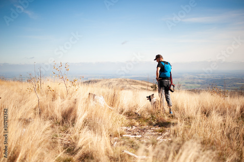 Man standing with his dog on mountain meadow. Black and white border collie in high golden grass.