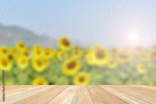 Empty top wooden table on soft focus blurred sunflowers in nature with sunlight