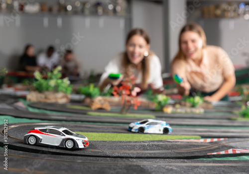 Emotional portrait of two women holding remote control and playing slot car racing