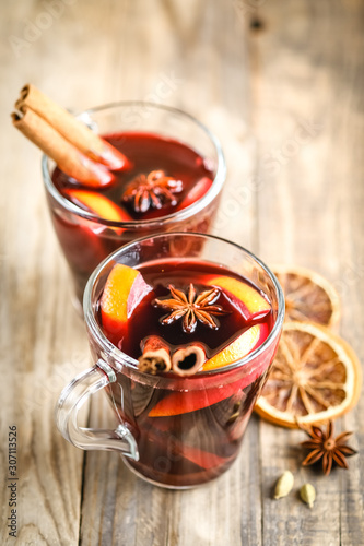 Mulled wine in glasses with apples, orange, cinnamon and star anise. Hot Christmas drink on a rustic background with copy space.