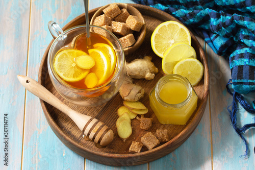 Cup of hot tea with lemon, ginger, honeycomb and honey on a wooden table.