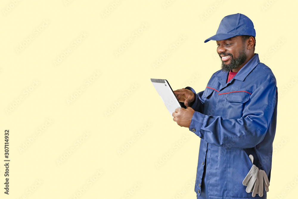 African-American car mechanic with tablet computer on color background African-American car mechanic with tablet computer on color background
