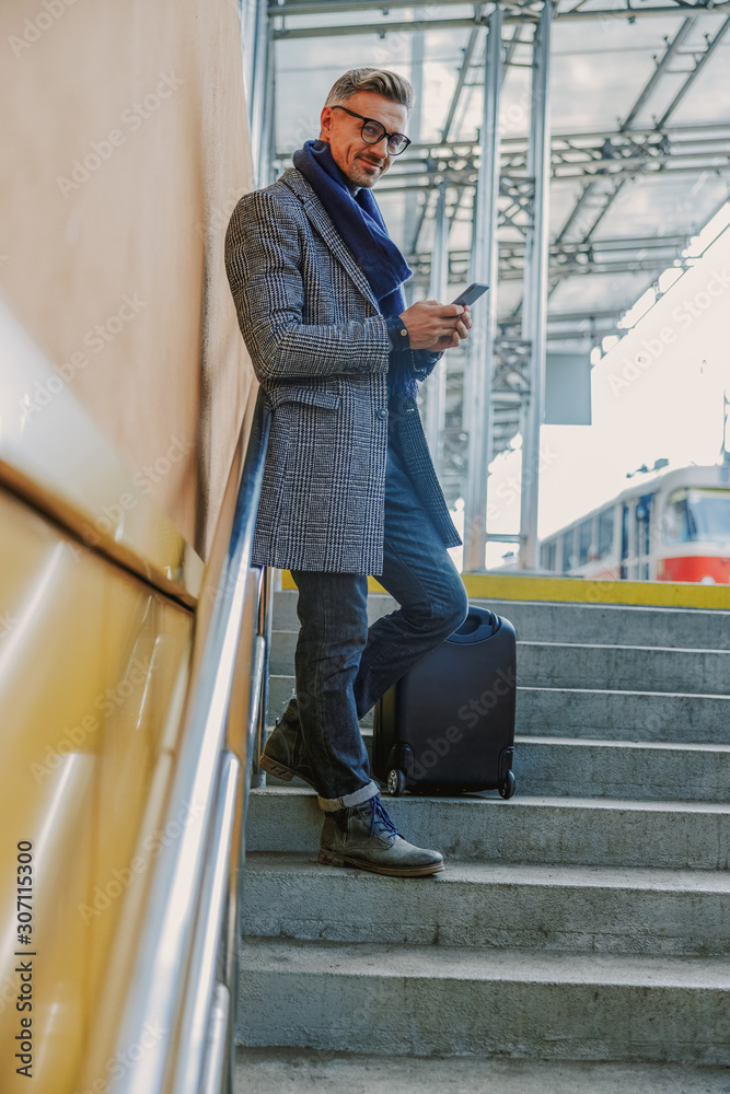 Good-looking young man holding smartphone and smiling Good-looking young man holding smartphone and smiling