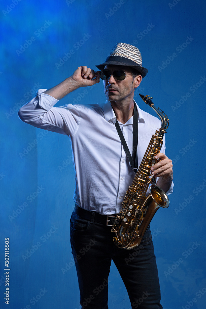 Naklejka premium Mann mit Altsaxophon vor blauem Hintergrund