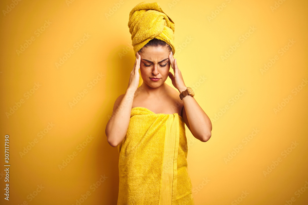 Young beautiful woman wearing towel after shower over isolated yellow