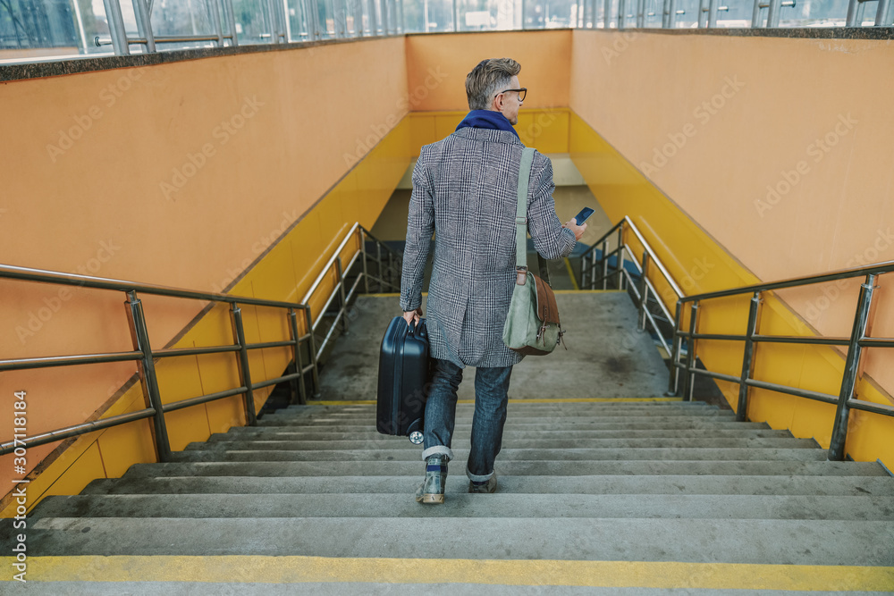 Stylish gentleman walking down the stairs and using smartphone Stylish gentleman walking down the stairs and using smartphone