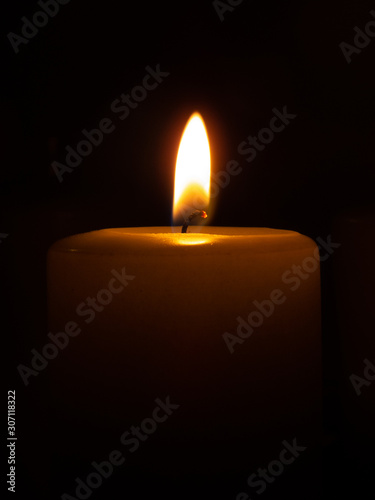 Partly visible lighted candle infront of black background