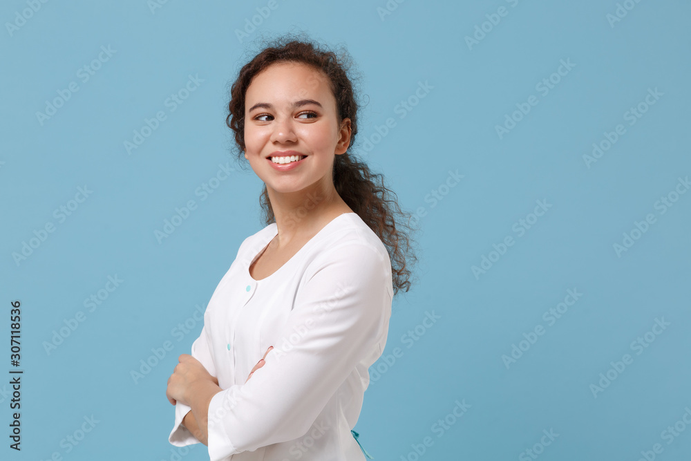 Side view of african american doctor woman isolated on blue background. Female doctor in white medical gown holding hands crossed. Healthcare personnel health medicine concept. Mock up copy space. Side view of african american doctor woman isolated on blue background. Female doctor in white medical gown holding hands crossed. Healthcare personnel health medicine concept. Mock up copy space.