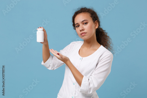 African american female doctor woman in medical gown point hand on medication tablets, aspirin pills in bottle isolated on blue background. Healthcare personnel medicine concept. Mock up copy space. © ViDi Studio