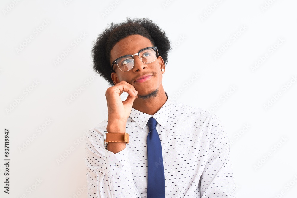Young african american businessman wearing tie and glasses over isolated white background with hand on chin thinking about question, pensive expression. Smiling with thoughtful face. Doubt concept. Young african american businessman wearing tie and glasses over isolated white background with hand on chin thinking about question, pensive expression. Smiling with thoughtful face. Doubt concept.