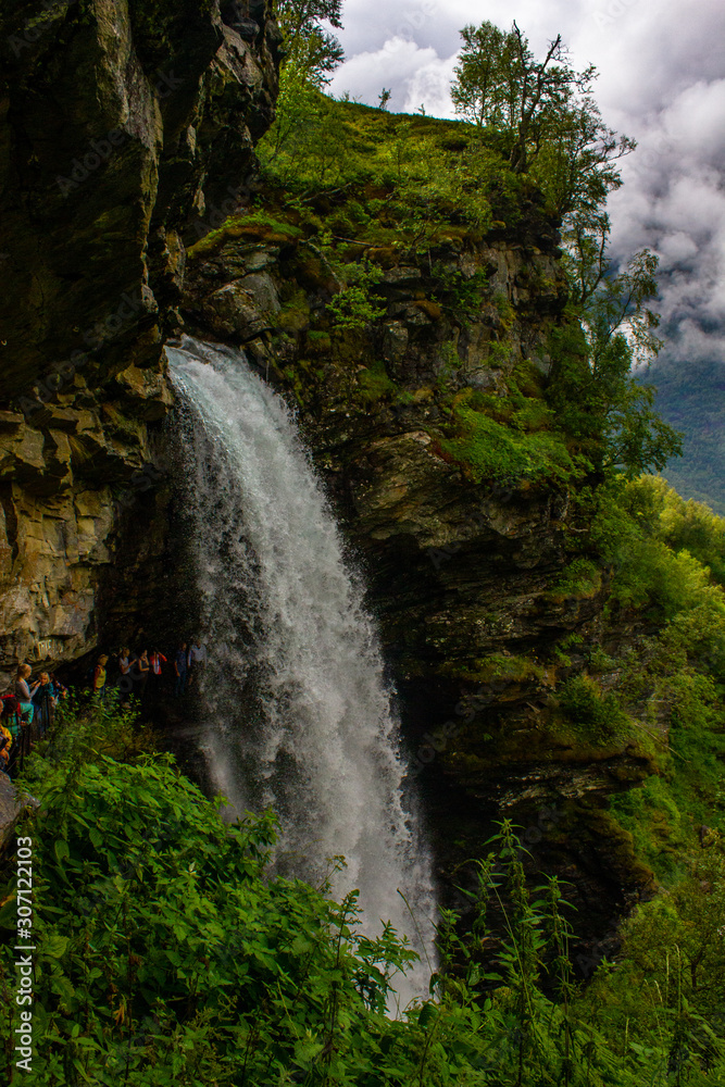 Obraz premium View of the waterfall and rock, you can get inside it by walking along the edge of the rock. Around all the green trees