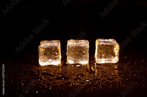 Golden ice cubes on black background. © peterkai