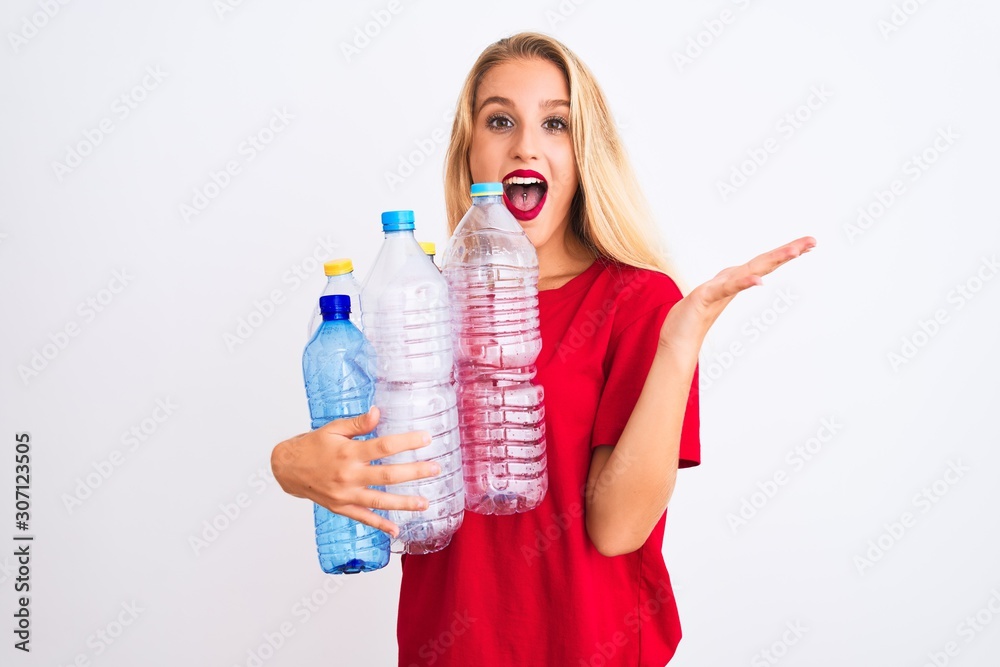 Young beautiful woman recycling plastic bottles standing over isolated white background very happy and excited, winner expression celebrating victory screaming with big smile and raised hands Young beautiful woman recycling plastic bottles standing over isolated white background very happy and excited, winner expression celebrating victory screaming with big smile and raised hands
