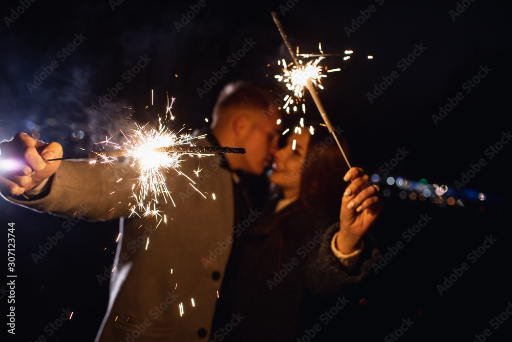 Fototapeta premium Romantic couple in love celebrate together the new year start or event party nightlife with fire sparkler