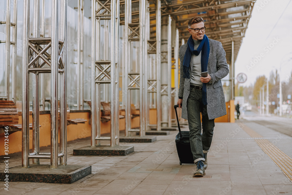 Gorgeous man holding cellphone and walking on the street Gorgeous man holding cellphone and walking on the street