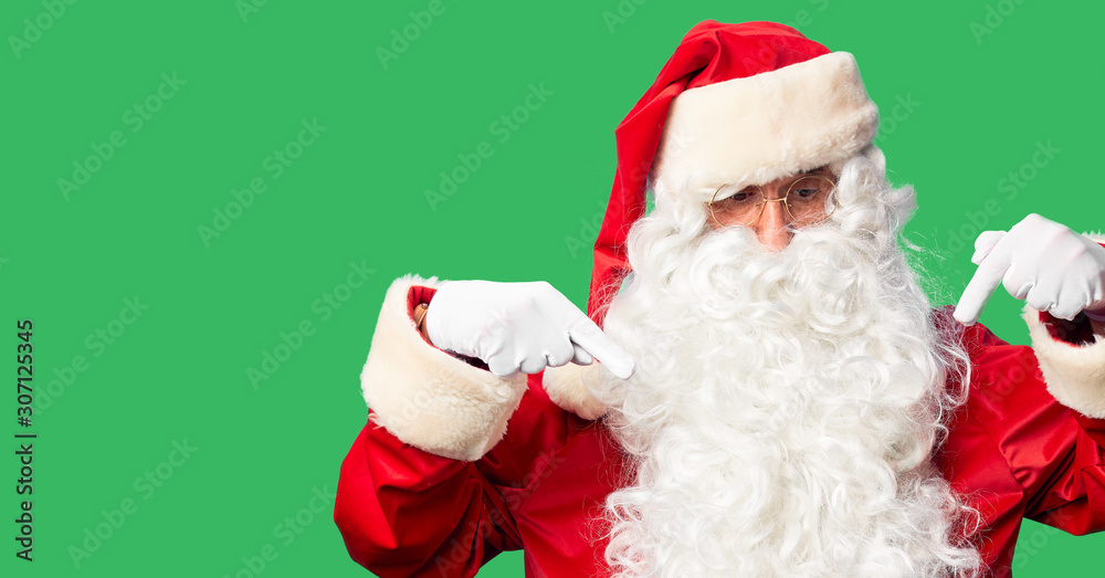 Middle age handsome man wearing Santa Claus costume and beard standing Pointing down looking sad and upset, indicating direction with fingers, unhappy and depressed.