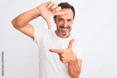 Middle age handsome man wearing casual t-shirt standing over isolated white background smiling making frame with hands and fingers with happy face. Creativity and photography concept.