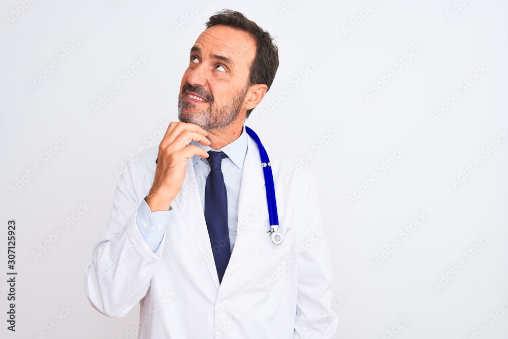 Middle age doctor man wearing coat and stethoscope standing over isolated white background with hand on chin thinking about question, pensive expression. Smiling with thoughtful face. Doubt concept. Middle age doctor man wearing coat and stethoscope standing over isolated white background with hand on chin thinking about question, pensive expression. Smiling with thoughtful face. Doubt concept.