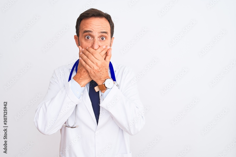 Middle age doctor man wearing coat and stethoscope standing over isolated white background shocked covering mouth with hands for mistake. Secret concept. Middle age doctor man wearing coat and stethoscope standing over isolated white background shocked covering mouth with hands for mistake. Secret concept.