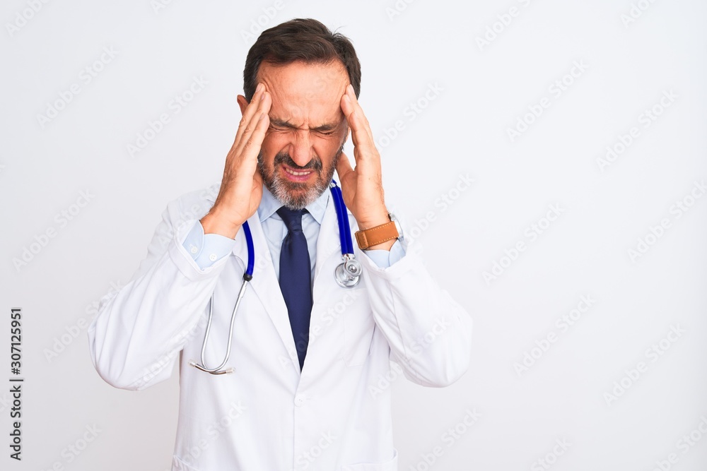 Middle age doctor man wearing coat and stethoscope standing over isolated white background with hand on head for pain in head because stress. Suffering migraine. Middle age doctor man wearing coat and stethoscope standing over isolated white background with hand on head for pain in head because stress. Suffering migraine.