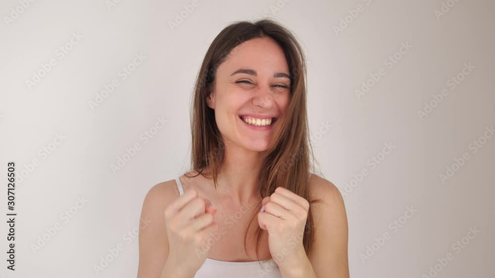 Young beautiful girl actively shows joy, smiles and waves her hands, having learned that she won the lottery. Portrait on a white background. 4k Young beautiful girl actively shows joy, smiles and waves her hands, having learned that she won the lottery. Portrait on a white background. 4k