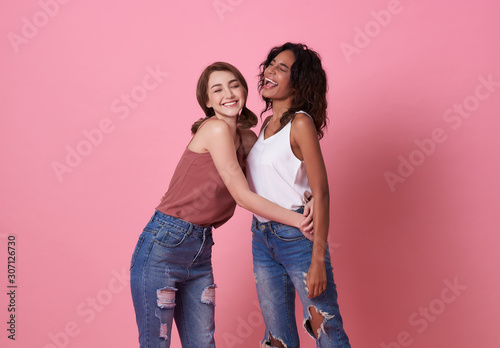 Fotografiet Happy smiling beautiful girl friend hug and wearing casual comfortable shirts isolated on pink background
