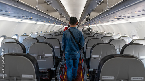 The back view of a man in a blue shirt on the plane walking away from the plane
