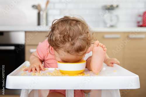 Toddler in high chair eating pasta straight from bowl photo