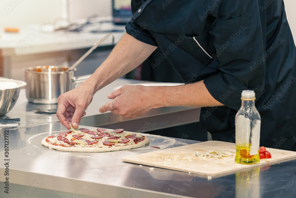 Closeup of a cook preparing pizza
