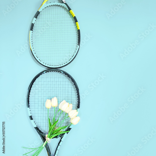 Concept mades of tennis rackets with white tulips on pastel blue background. photo
