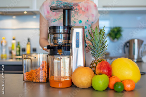 Bilde på lerret Woman making fruit juice using juicer machine in home kitchen, healthy eating li