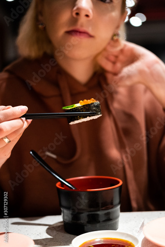  young girl eat sushi with chinese chopsticks in restaurant 