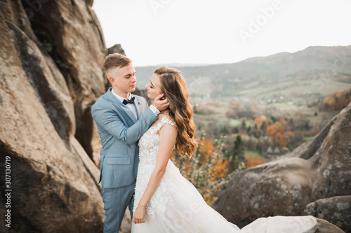 Beautiful gorgeous bride posing to groom and having fun near at mountains with amazing view, space for text, wedding couple © olegparylyak