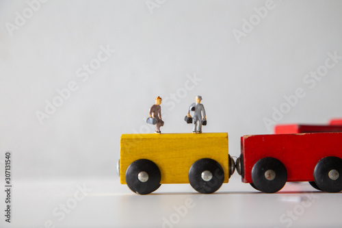 Miniature people car works on a multicolored Wooden car on a white wooden table, Creative background Teamwork for global transportation, Concept: Education for children learning in school