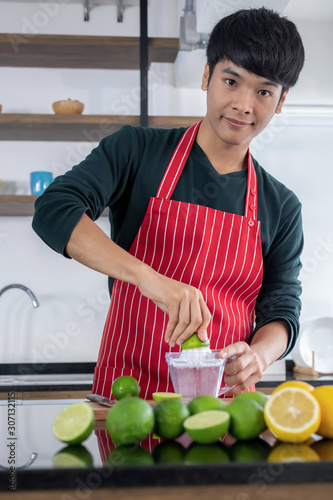 Young men squeezing lemonade in the kitchen