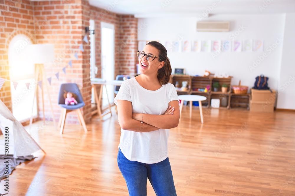 Young beautiful teacher wearing glasses standing at kindergarten Young beautiful teacher wearing glasses standing at kindergarten