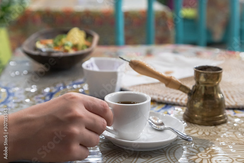 White coffee cup and coffee in a copper coffee pot